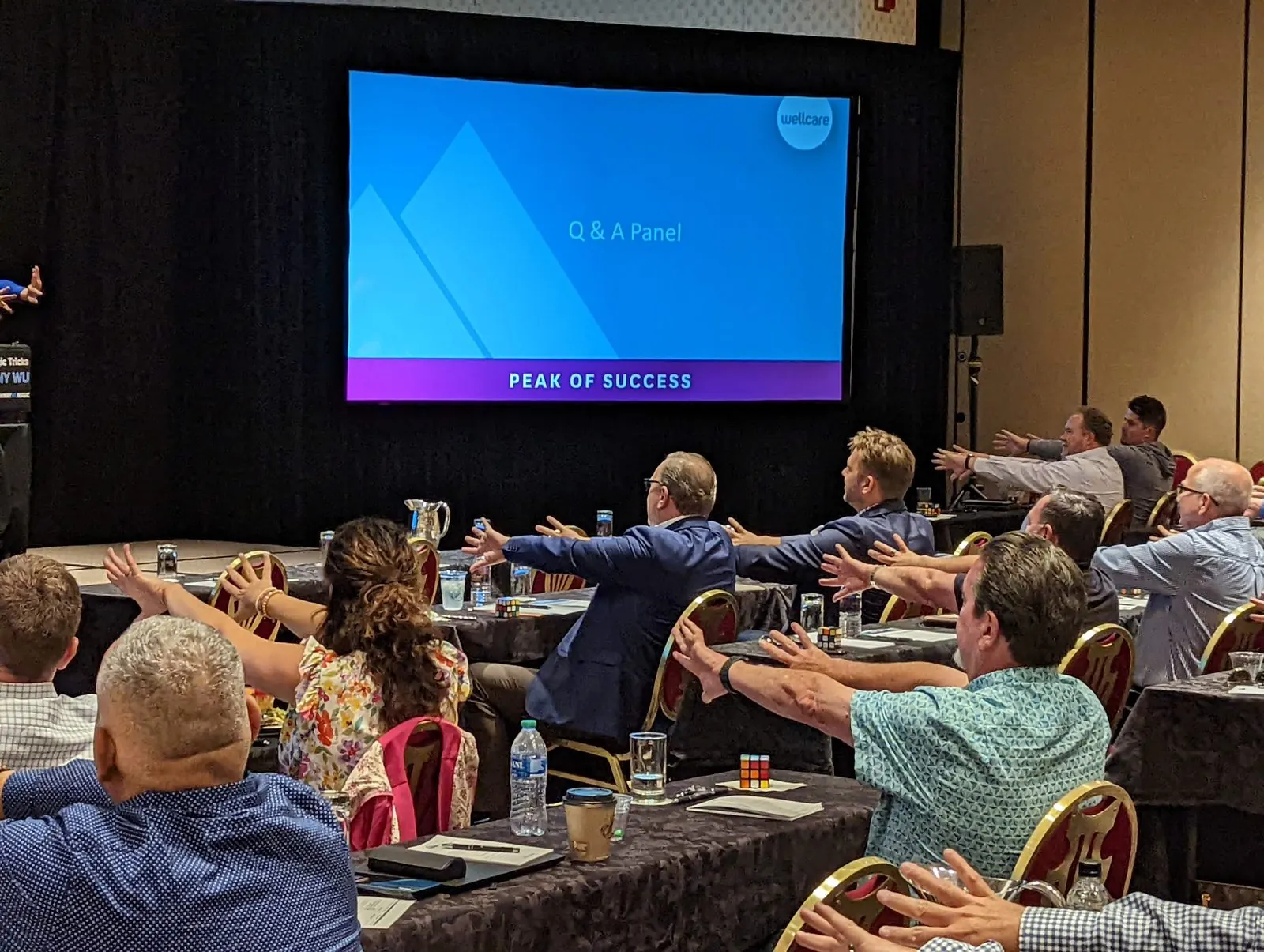 A full sales conference audience at The Broadmoor with arms stretched out in unison, joining in on a demonstration with Johnny Wu