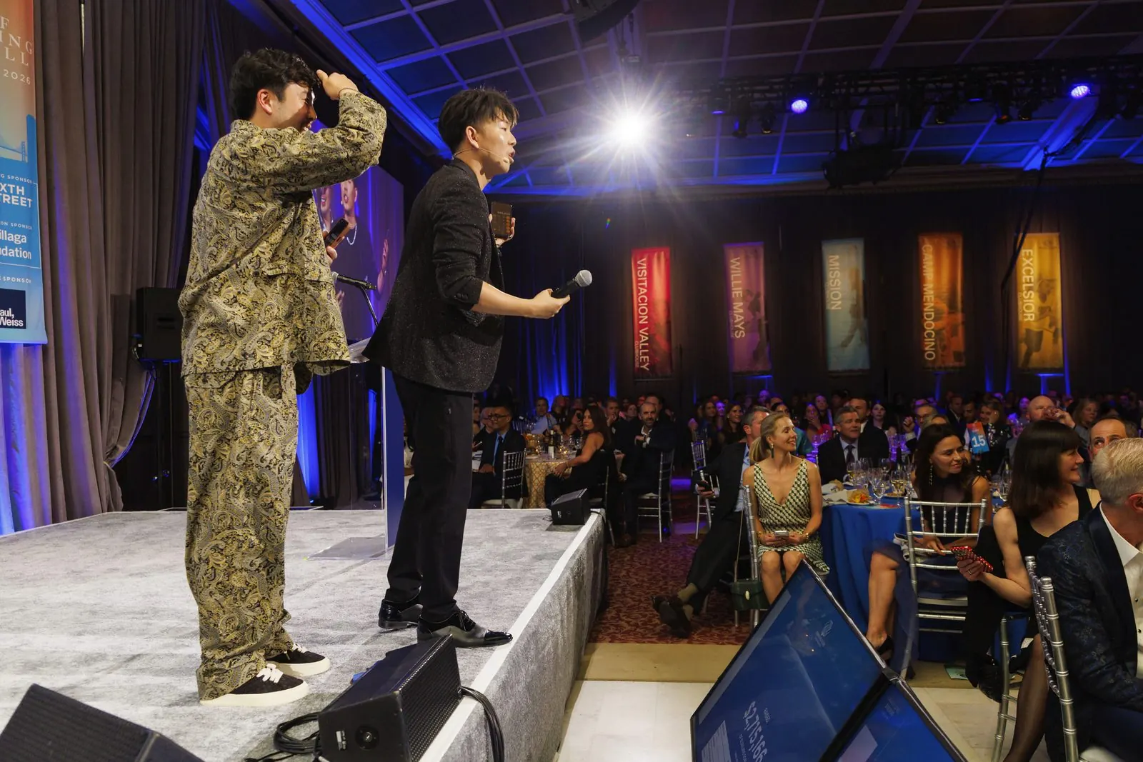 Johnny Wu on stage in front of a full gala ballroom