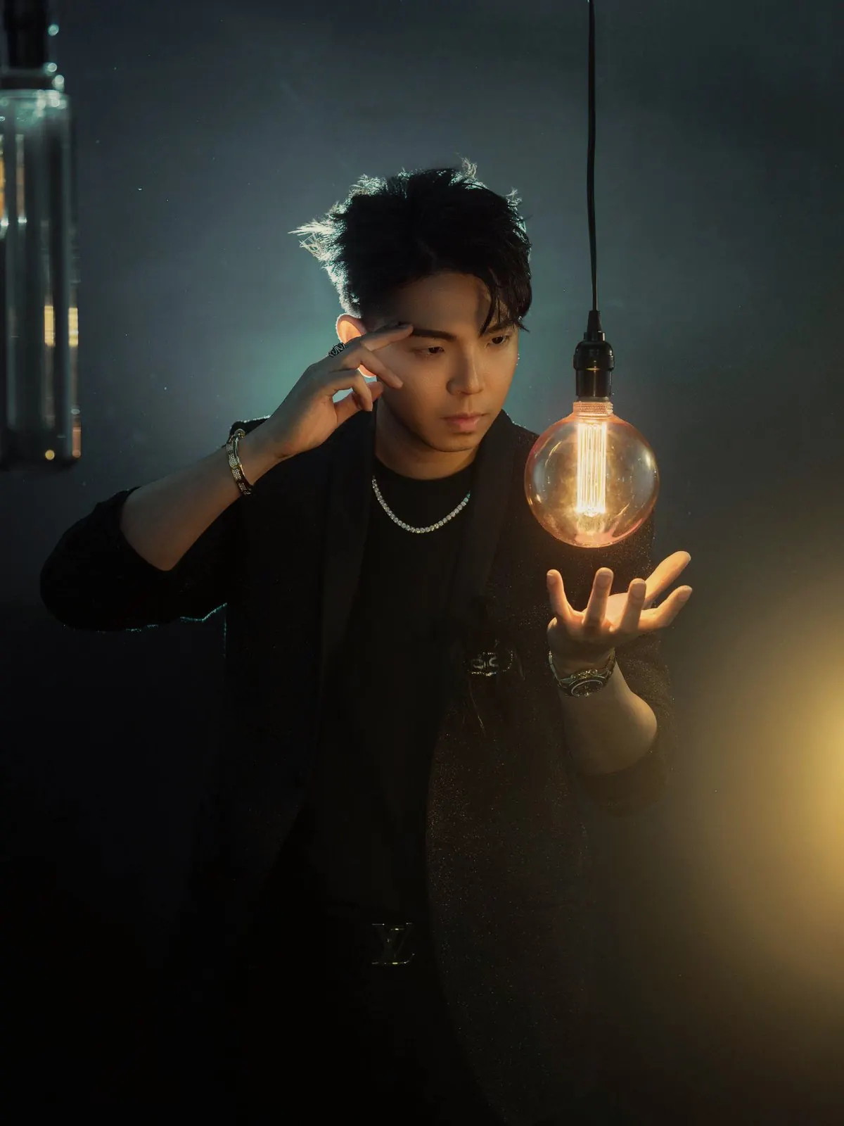 Portrait of Johnny Wu, mentalist and keynote speaker, with one hand to his temple and a glowing light bulb floating above his other hand